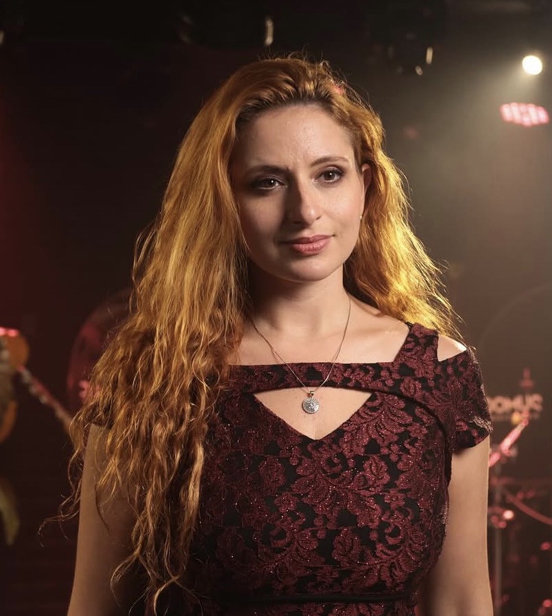 Cantora ruiva em vestido bordô em apresentação ao vivo