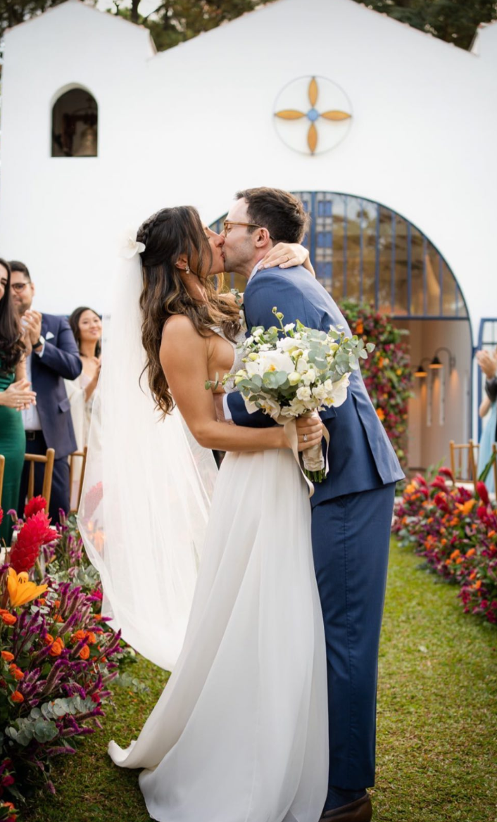 Casal se beijando na entrada da capela após a cerimônia